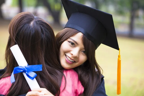 Young female graduate hugging her friend at graduation ceremony