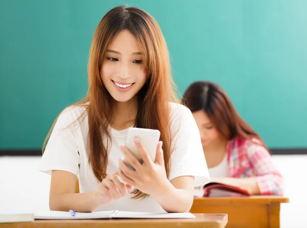 Young female student using smart phone in classroom