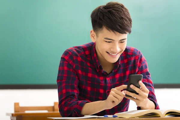 Happy student reading smart phone in classroom
