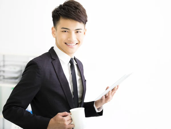 Happy young  businessman holding tablet in office