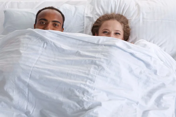 Man and woman look out from under the blanket