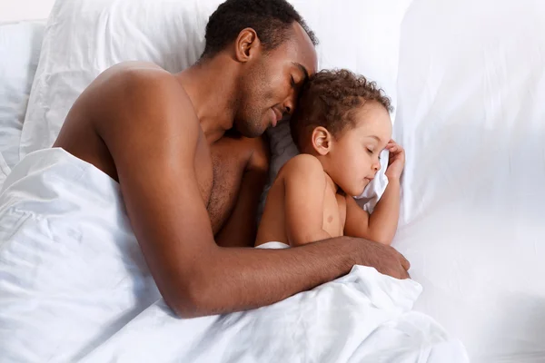 Father and son sleeping in bed, family relationship.