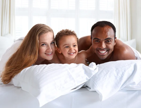 Parents and son  on white bed in the bedroom.