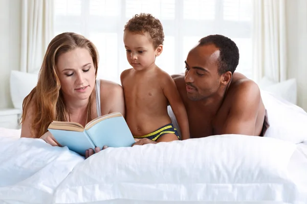 Mother and father reading with her son on bed.