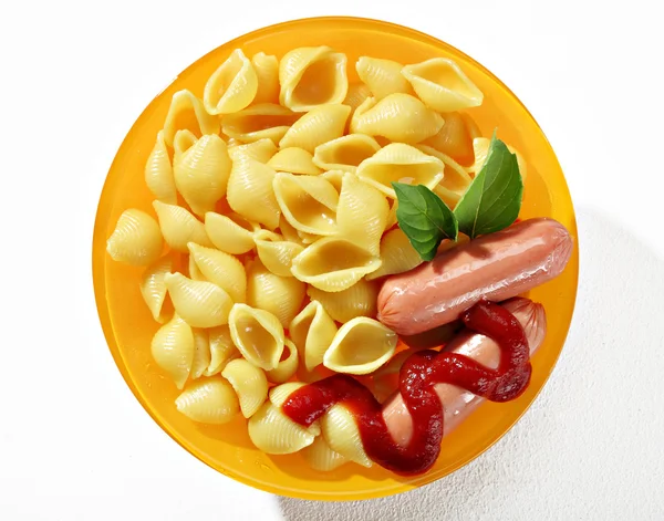 Expertly cooked macaroni shells with sausages in orange plate