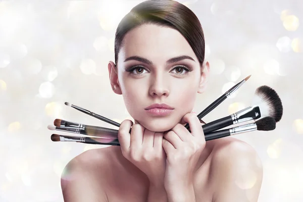 Young beautiful woman with makeup brushes near her face, skin care concept