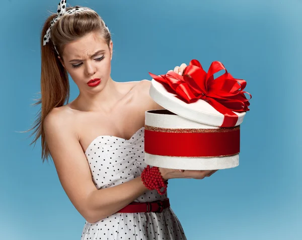 Thoughtful girl holding holiday or birthday presents, gift box on blue background. Holidays, celebration, birthday concept