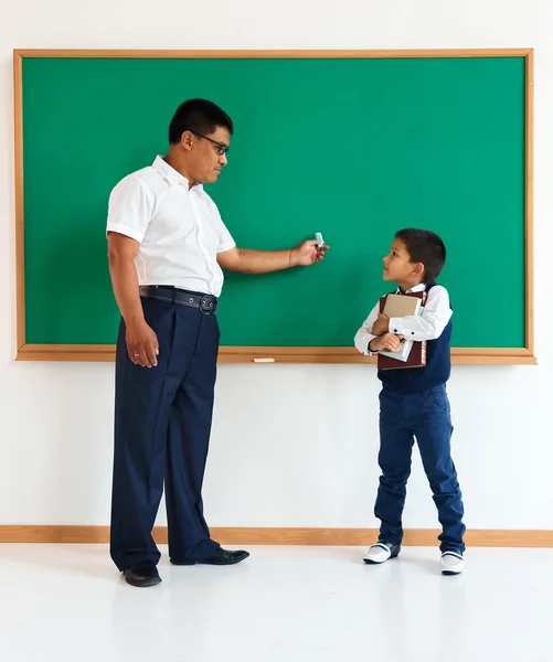A student with teacher near blackboard in the classroom
