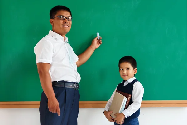 A student with teacher near blackboard in the classroom