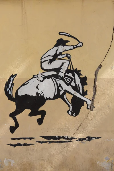 Graffiti of rodeo, man riding horse. Old Wall, Argentina