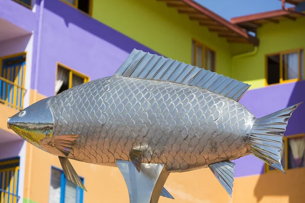 Square with silver fish statue and colorful facades, Guatape
