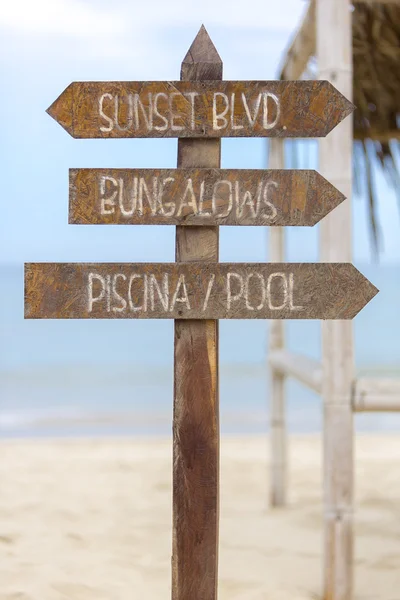 Wooden sign post to bungalows and the pool on beach, Peru