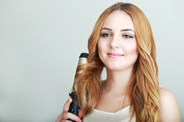 Beautiful woman with curling iron