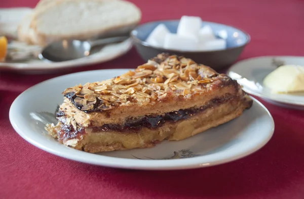 Piece of handmade cake with almonds and currant jam