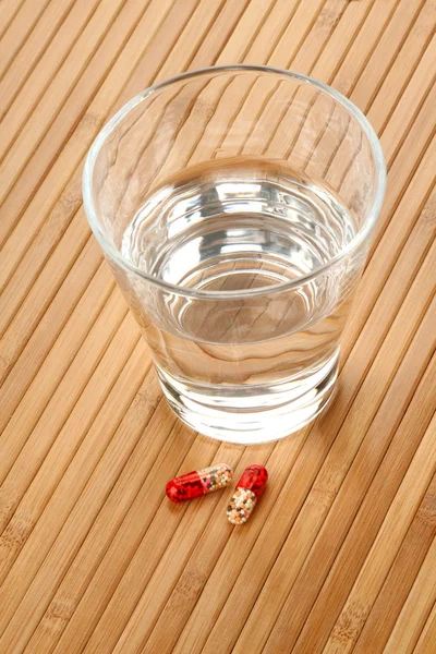 Glass of Water and Medicine Pills on Wooden Background