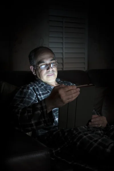 Man reading tablet at night