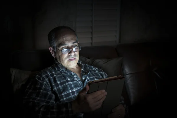 Man reading tablet at night