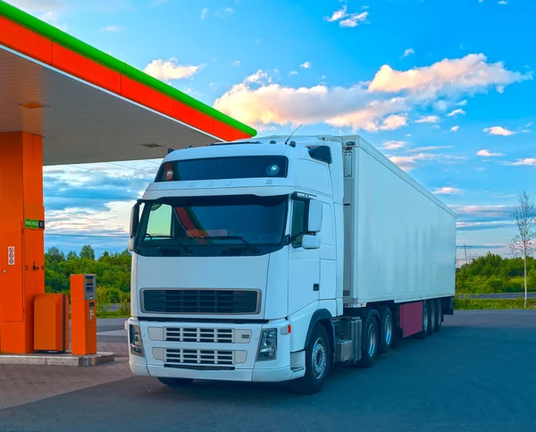 White truck is at the fuel station in sunny summer day