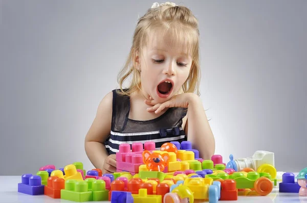 Portrait of beautiful little girl playing with plastic toy cubes