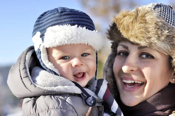 Happy family. Young mother in a winter park with her sweet baby