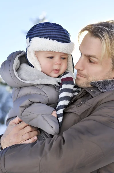 Happy family. Portrait of young father in a winter park with his sweet baby boy