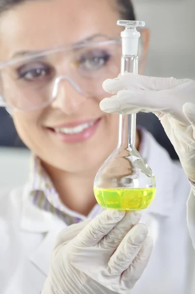 Attractive young PhD student scientist observing the green indicator color shift after the solution destillation in chemical laboratory