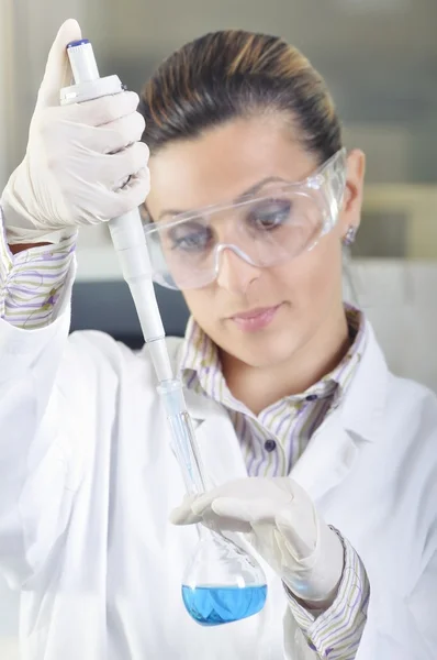 Attractive young PhD student scientist observing the blue indicator color shift after the solution destillation in chemical laboratory