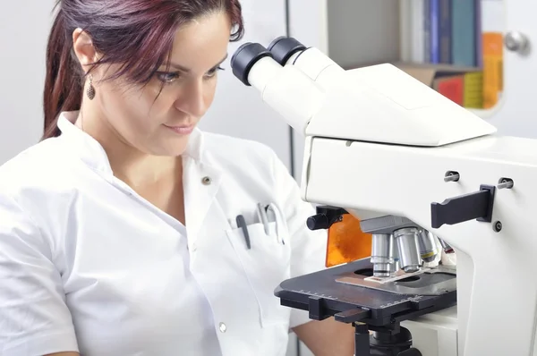 Young scientist studying new substance or virus in microscope