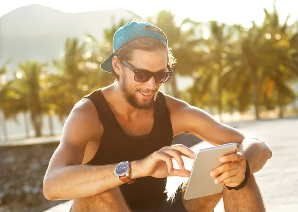 Fashion guy sitting on the tablet, running in sunglasses on the