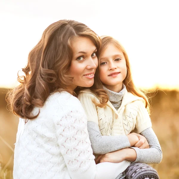 Mother and daughter walking in autumn in a field