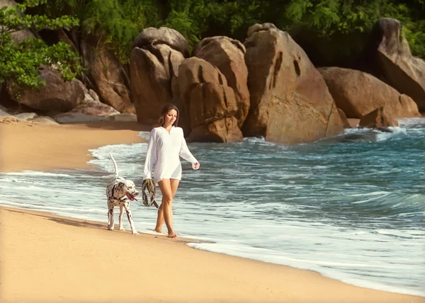 Girl walk on the beach with the dog Dalmatia