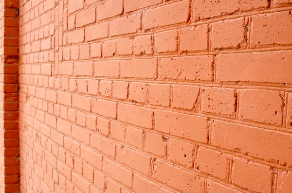 Angle view of a brick wall with a layer of red paint