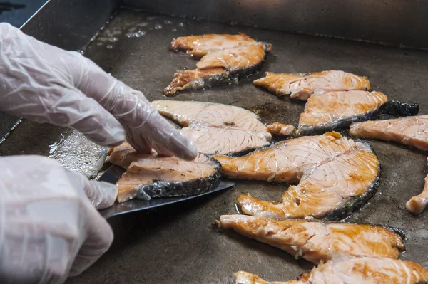 Salmon steak cooking on grill at a restaurant buffet
