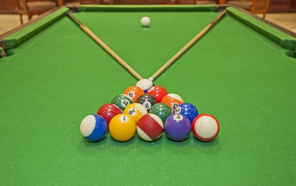 Closeup of a pool table with balls and cues