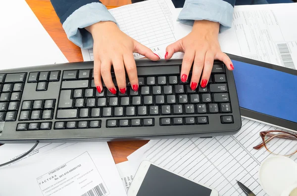 Closeup office womans fingers with red nailpolish writing on computer keyboard using both hands