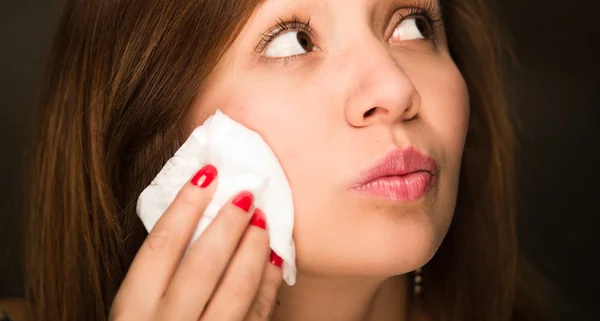 Brunette woman closeup face using cotton pads on chin