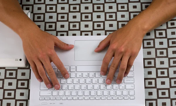 White laptop as seen from above with hands typing on keyboard