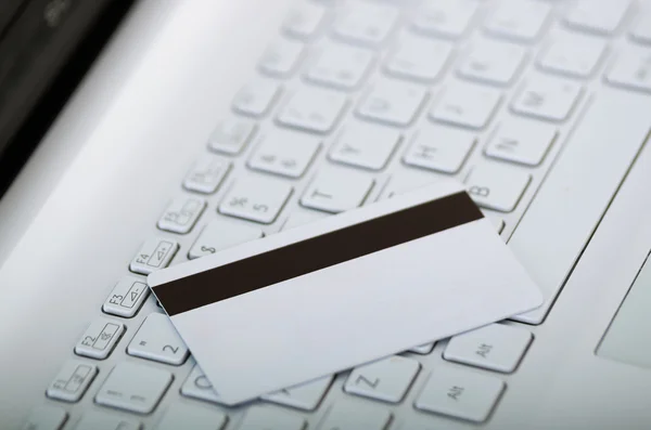 Closeup white electronic swipe card with magnetic stripe visible lying on computer keyboard