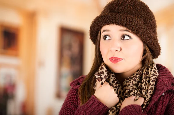 Pretty young brunette woman wearing red jacket, hat and scarf, naturally posing
