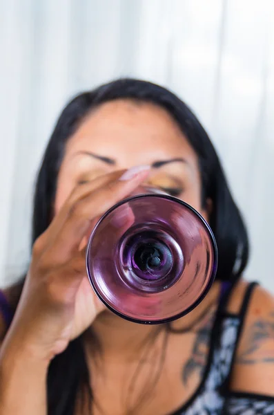 Brunette closeup lifting glass up and drinking, bottom facing camera