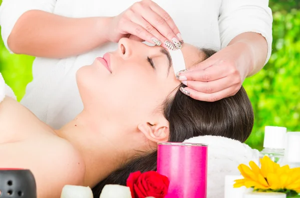 Closeup womans face receiving facial hair wax treatment, beauty and fashion concept