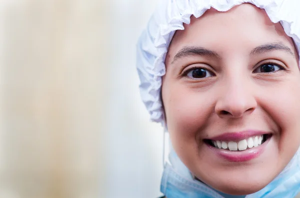 Closeup headshot female nurse wearing bouffant cap and smiling happily for camera