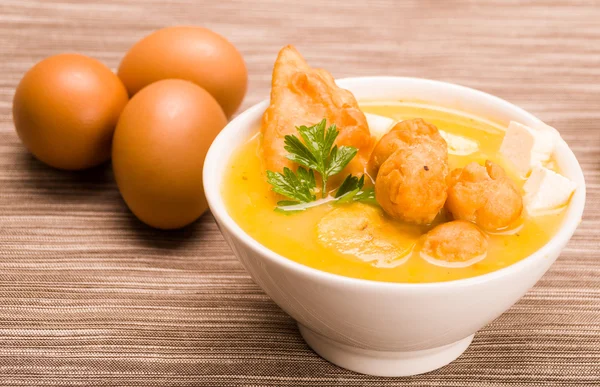 Closeup table setting with serving of traditional fanesca soup and eggs working as decor