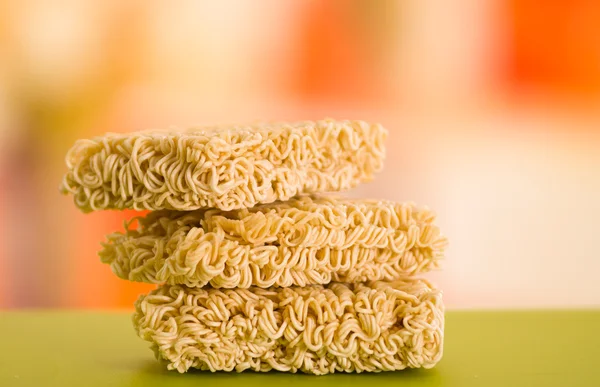 Noodles square blocks stacked on top of each other, green surface and blurry background