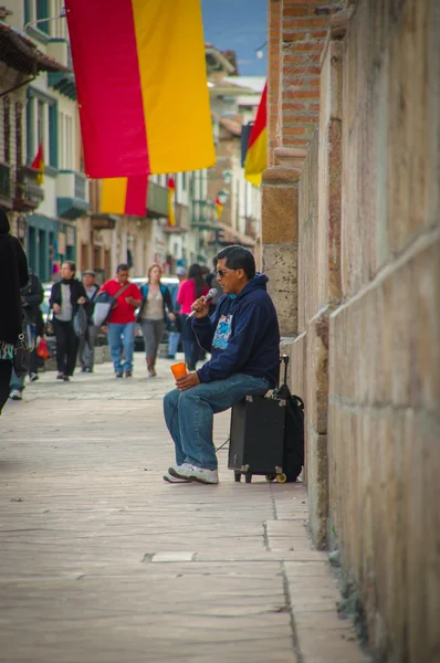 Cuenca, Ecuador - April 22, 2015: Street performer sitting back against wall on top of amplifier singing in city streets