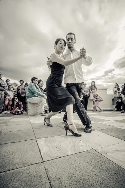 Cuenca, Ecuador - April 22, 2015: Couple performing latin dance styles on city square in front of small crowd, black and white edition