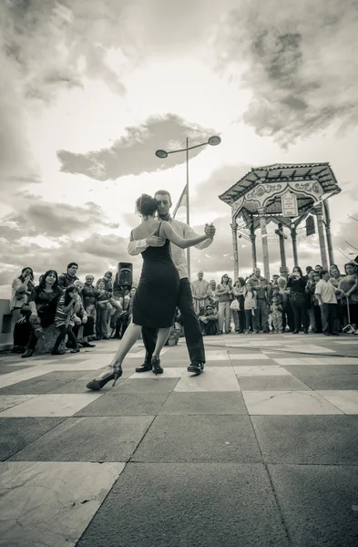 Cuenca, Ecuador - April 22, 2015: Couple performing latin dance styles on city square in front of small crowd, black and white edition