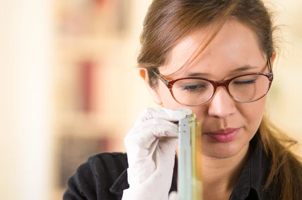 Young woman wearing black shirt holding up toner parts and looking closely into it while performing maintenance, concentrated facial expressions