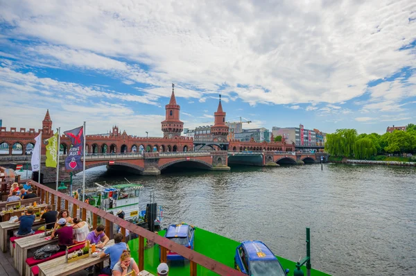 BERLIN, GERMANY - JUNE 06, 2015: Spree river cross under oberbaumbrucke, people havind relaxing time on the side