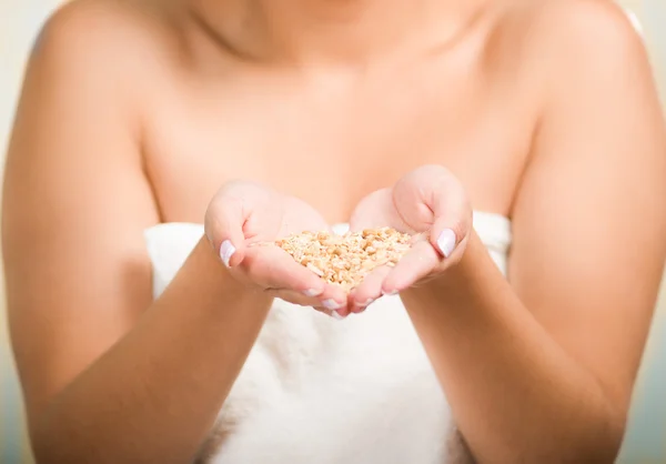 Closeup woman naked shoulders and towel wrapped around chest, pouring granola into her own hands